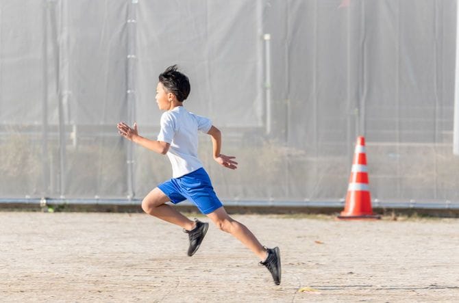 校庭をきれいなフォームで走る小学生