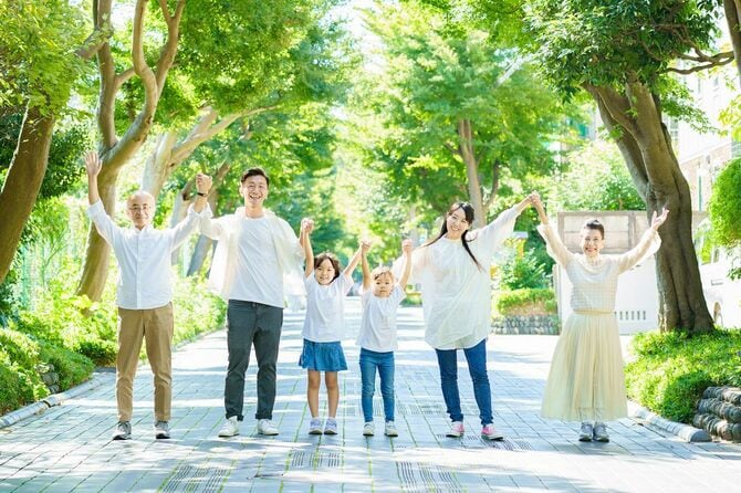 緑豊かな通りで手をつないでいる3世代の家族