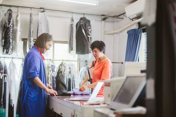 クリーニング店の店員と会話する女性客