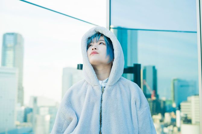 空を見上げるフードを被った青い髪の女性