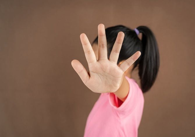 ブラウンバックグロンで停止ジェスチャーを作る小さな女の子