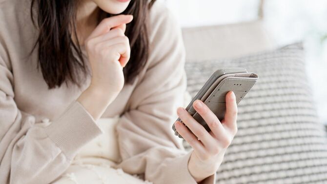 考えながらスマホを使用している女性