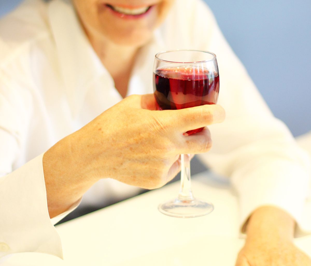 赤ワインを手に笑顔を見せるシニア女性