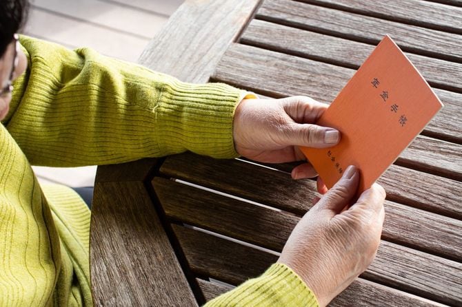 手にした年金手帳を見つめる女性