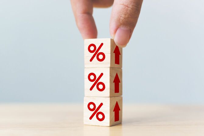 木製ブロックに赤い文字でパーセンテージマークと、上向きの矢印が描かれていて、それを積み上げている手元