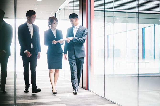 会社の廊下を歩き仕事の話をする社員