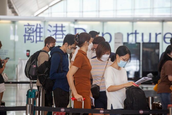 香港国際空港のチェックインカウンターに並ぶマスクをした人々