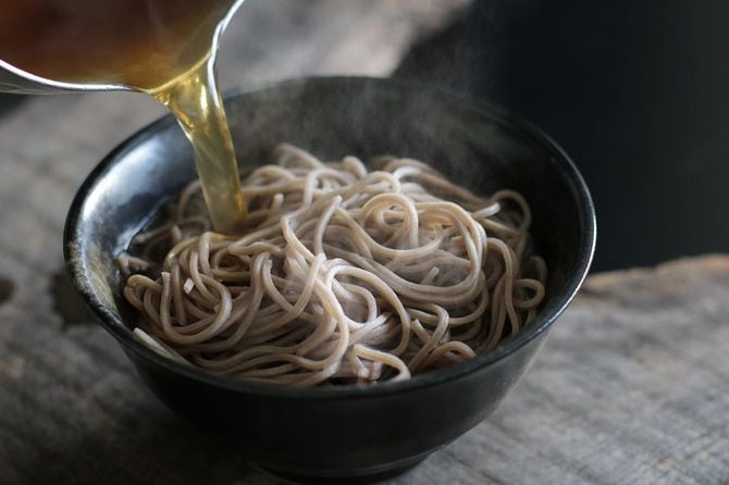 温かいそばにだしを注ぐ
