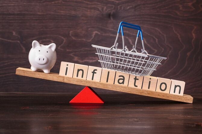 シーソーの上の貯金箱とinflationと書かれたブロック