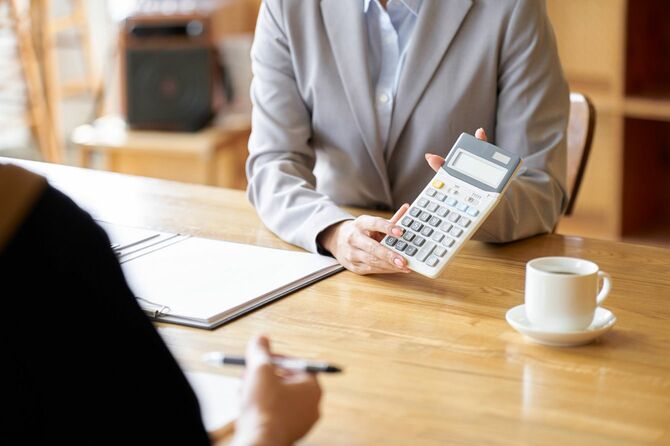 顧客に電卓の数字を見せるビジネスウーマン