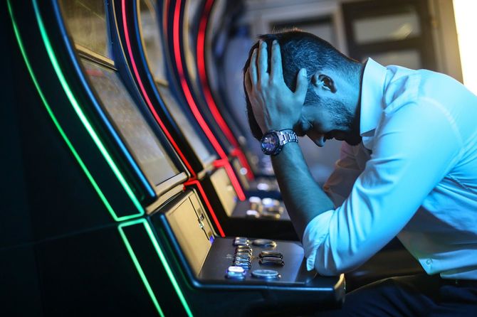 スロットマシンの前で頭を抱える男性