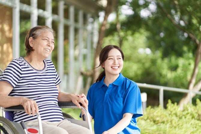 車椅子のシニア女性に付き添っている若い介護士