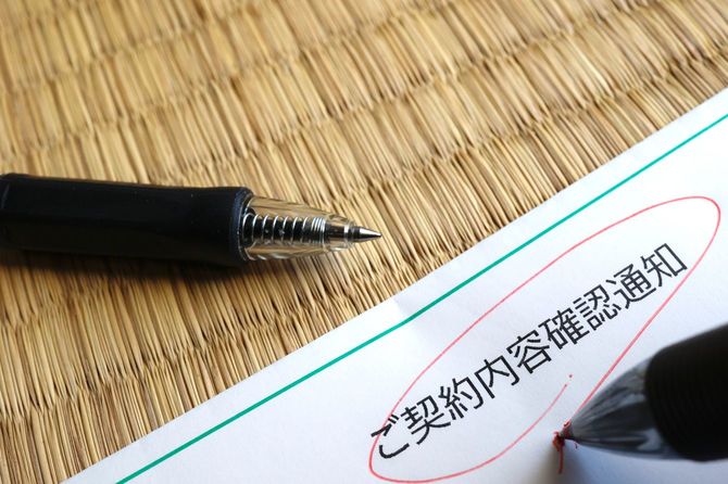 契約内容の確認通知に赤で丸をつけている手元