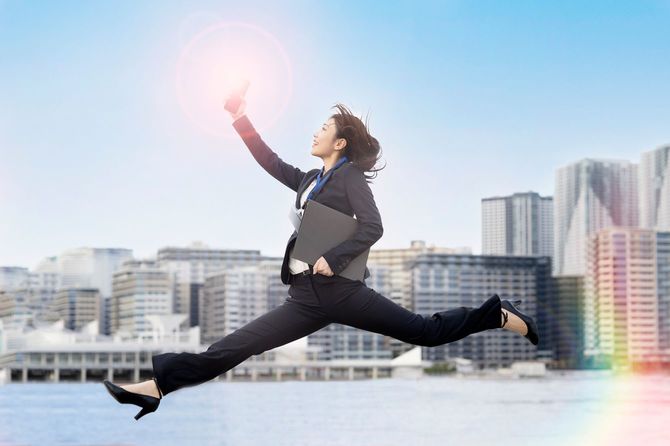 ビジネススーツで軽やかにジャンプする女性