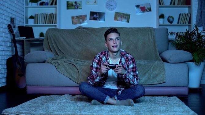 夜に部屋でビデオゲームをプレイする10代の少年