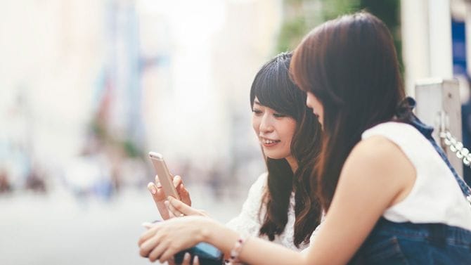 スマートフォンを見る若い女性2人組