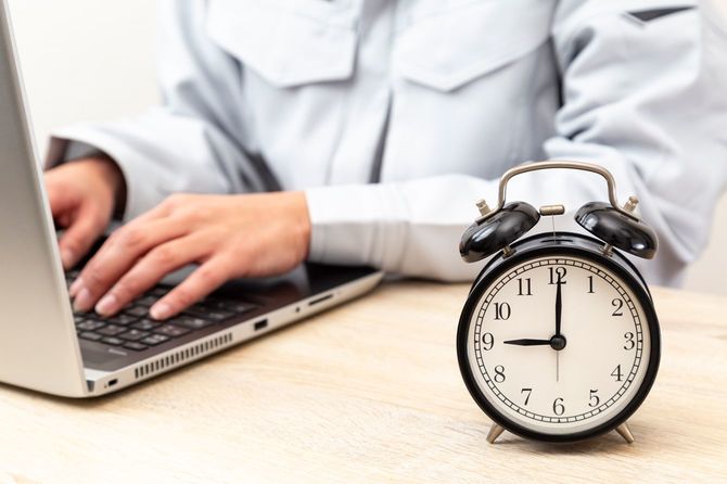時計とパソコンで作業する人