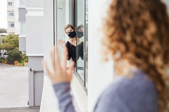 窓から顔を出し、隣人に手を振る人