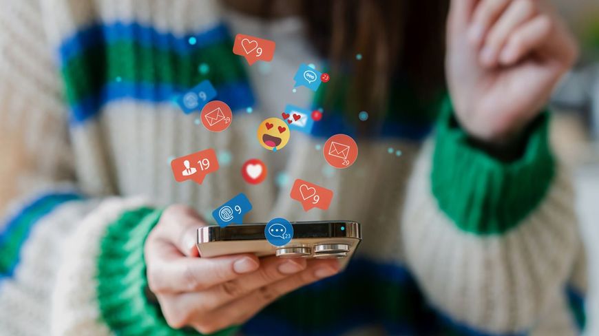 スマートフォンから浮かび上がるSNSのリアクションアイコン