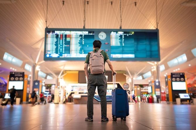 クアラルンプール国際空港の発着ボードを見る男性観光客