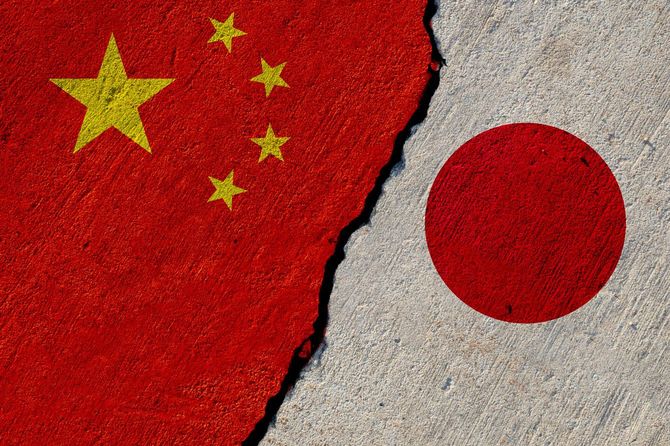 ひび割れたコンクリートの壁に描かれている、五星紅旗と日章旗