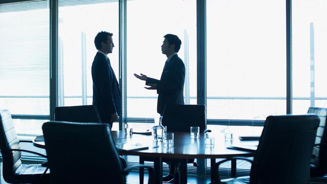 会議室で話し込む2人のビジネスパーソン