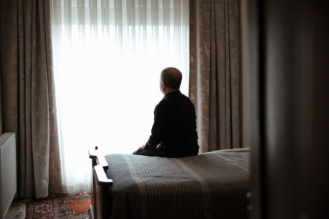 薄暗い部屋で窓の外を見る人のイメージ