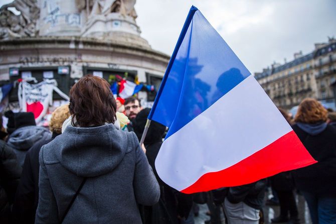フランスの国旗を手にデモに参加する人たち