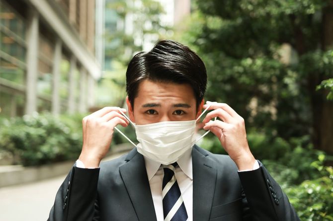 マスクを取るスーツ姿の男性