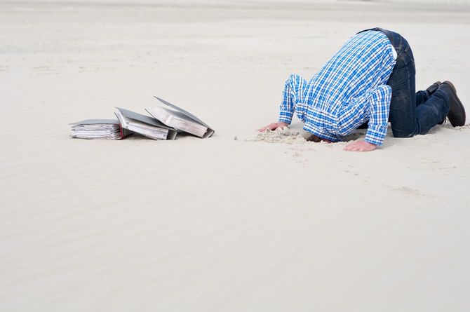 土下座で頭を砂に埋めるビジネスマン