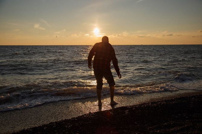 海に石を投げる男