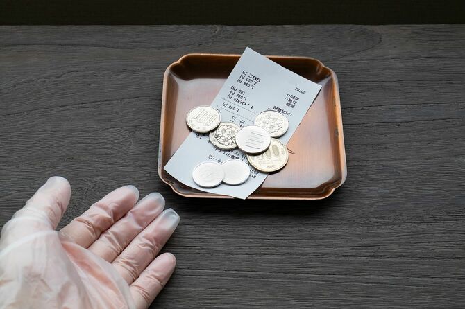 トレイに小銭を渡し、手袋をはめた店員