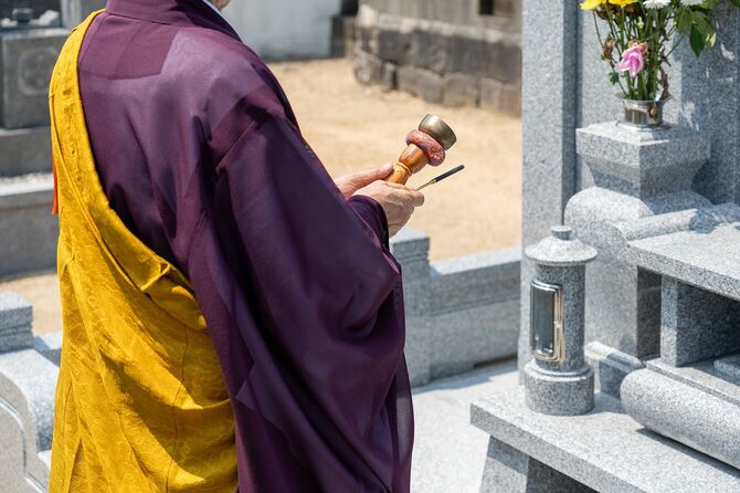 墓の前で祈る僧侶