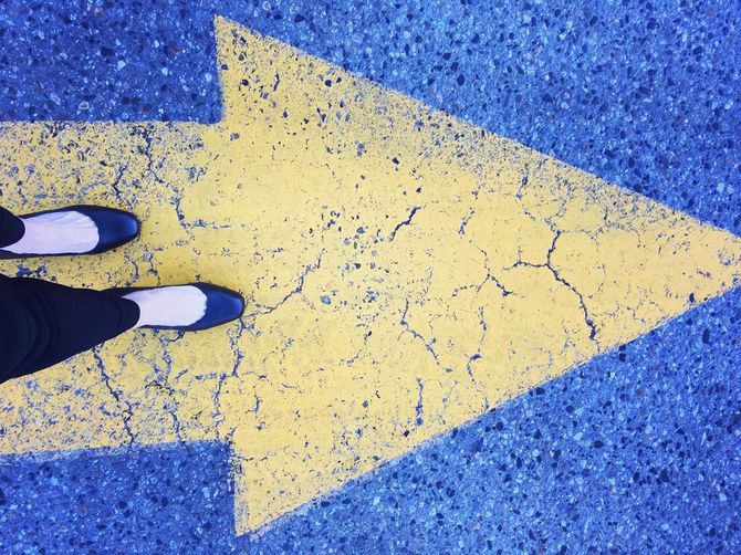 地面に描かれた矢印の方向に歩く女性の足元