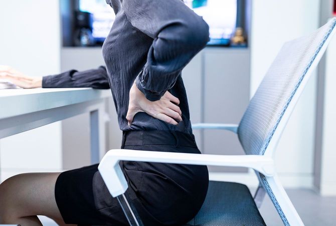 腰に手を当てて椅子に座っている女性