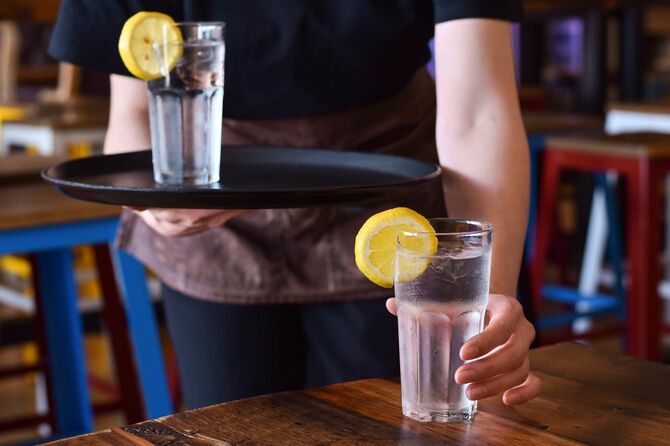 テーブルの上にレモンと冷たい水のガラスを置くレストランのサーバー