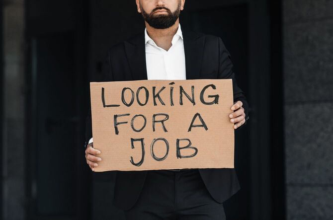 「仕事を探しています」と書かれたプラカードを持っている男性