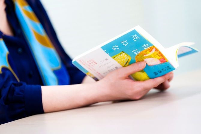 書籍を手に取りながら取材に応じる河合さん