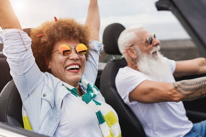 オープンカーでドライブを楽しんでいるシニアカップル