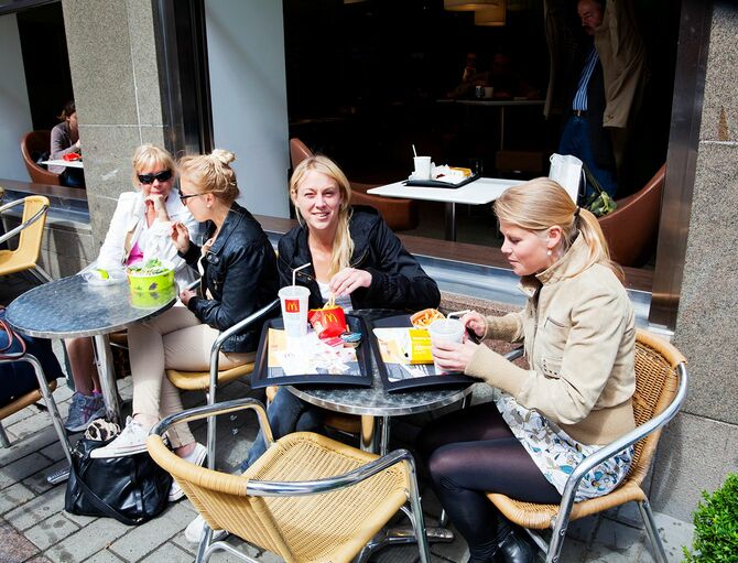 マクドナルドの外の歩道で食事をしている若い女性