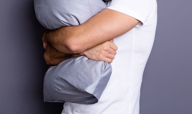 枕を抱きしめる男性