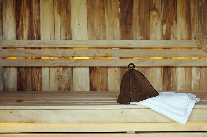 サウナの木の厚板からベンチに横たわるバスハットと白いタオル