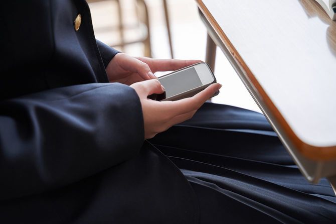 教室の席でこっそりスマホを使用している女子生徒の手元