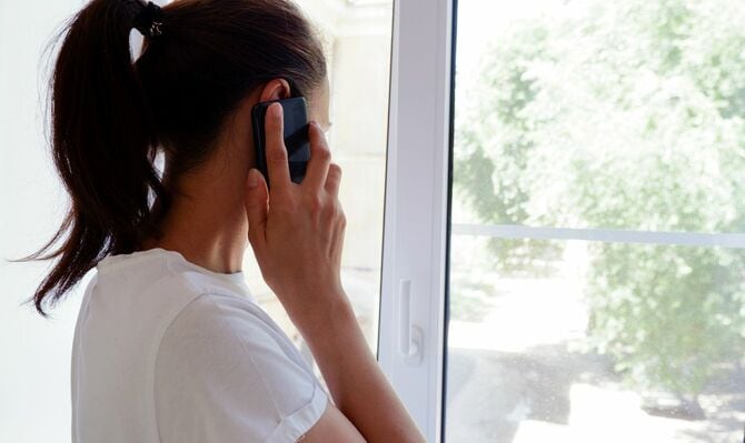 携帯電話で話し、窓の外を見ている若い女性