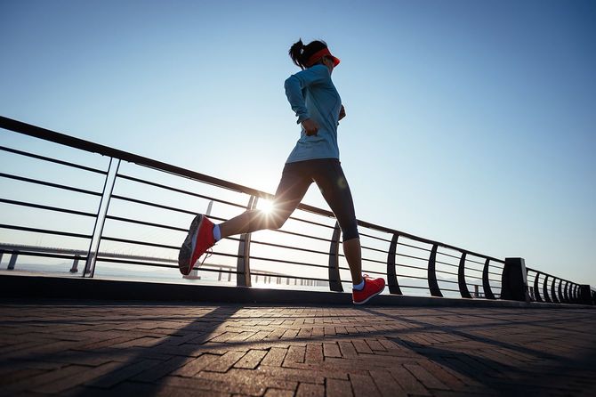 海辺の橋の上を走るフィットネスウーマンランナー