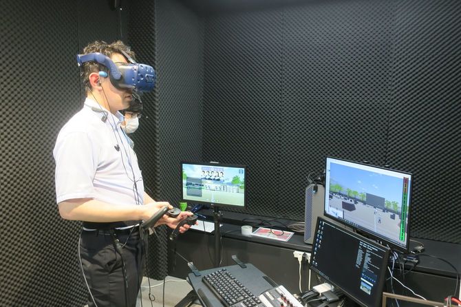 VRゴーグルを装着し、コントローラーでアバターを操作する川崎氏