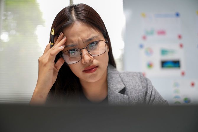 パソコンを見ながら仕事のストレスを感じる女性