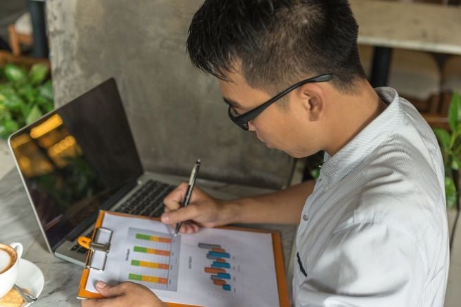 プリントアウトしたグラフにペンでメモをしている男性