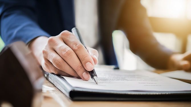 ペンと契約書を顧客に渡す