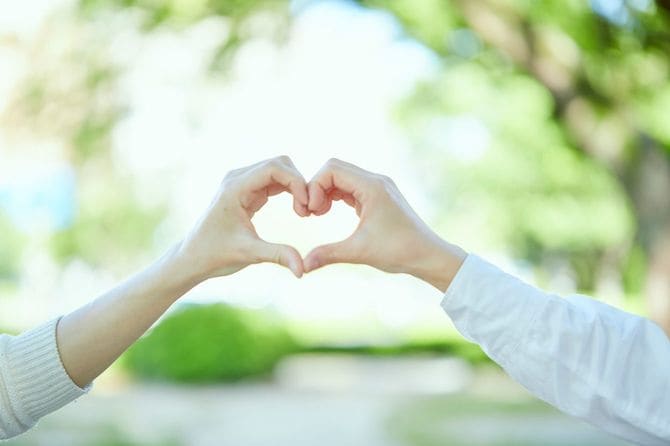 2人の手でハートマークをつくっているカップル